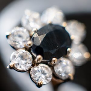 Gem-set 9ct Gold Ring Centered with an Oval Mixed-cut Dark Gemstone bordered by cubic zirconia
